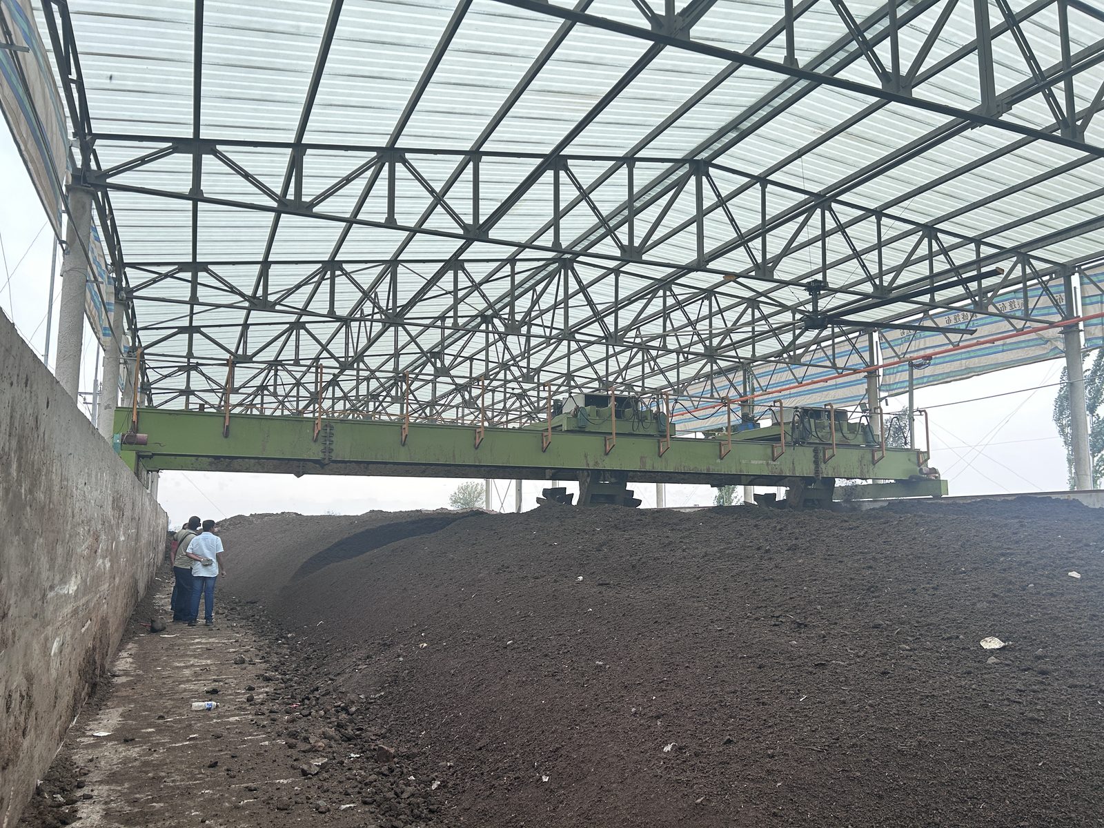 Large scale compost turner operating in a fermentation bay